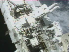 John Herrington, top, and Michael Lopez-Alegria, working outside the international space station during the first EVA. NASA TV image.