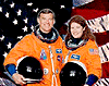 NASA photo of ISS crewmembers Voss and Helms in flight suits with US flag behind