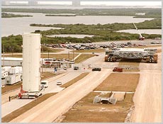 The payload canister (left), in its vertical position, arrives at Launch Pad 39A with the U.S. Lab Destiny inside. In the near background is a crawler-transporter. NASA photo.